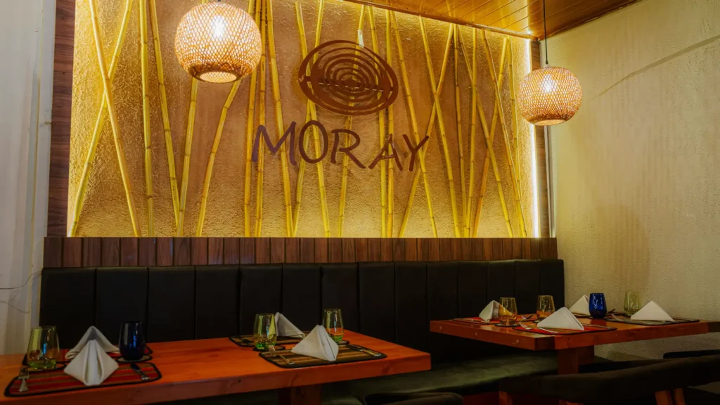 Golden wall with the Moray logo and tables set for dinner, Cusco