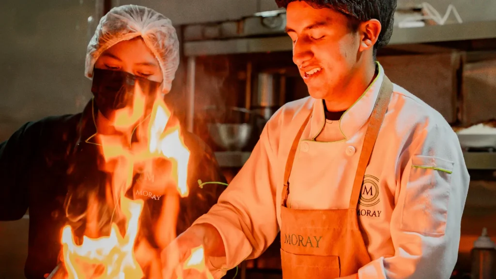 Cocinero flambeando una sartén en la cocina de Moray, Cusco