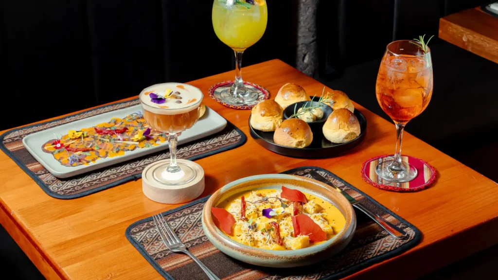 Table with house bread, cocktails and Andean dishes at Moray, Cusco
