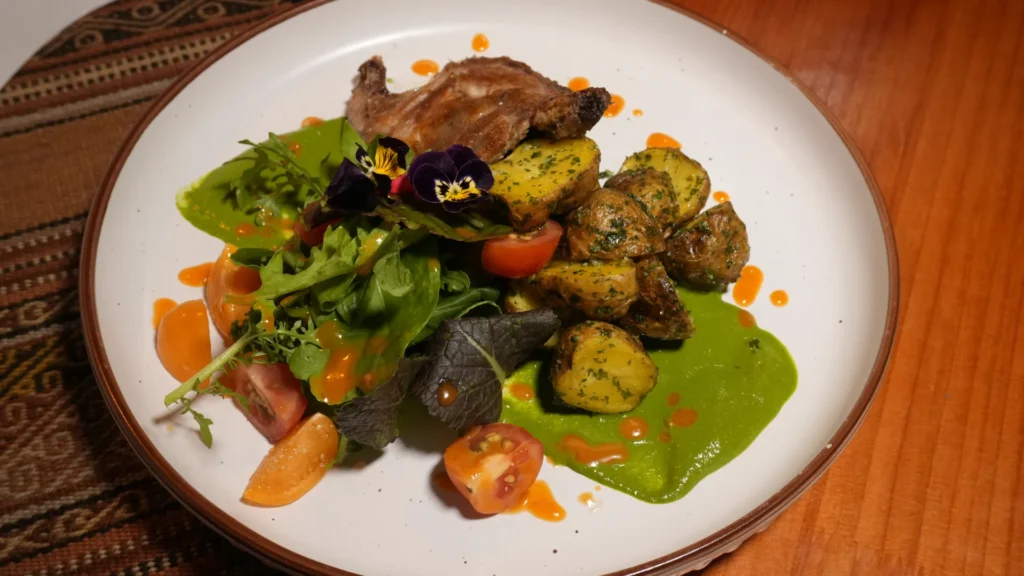 Cuy confitado plated with fresh salad at Moray, Cusco